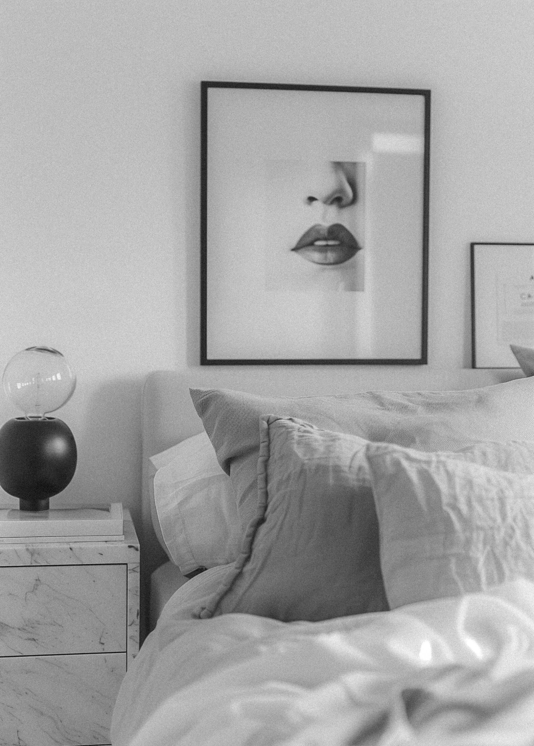 Black and white luxury bedroom with white bedding, marble nightstand, and fashion art print